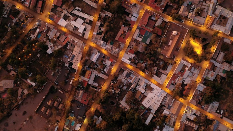 An aerial view of a sprawling modern city at night, with illuminated roads and dense buildings, showcasing complex urban infrastructure.