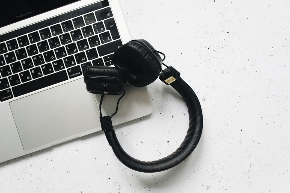 An organized desk layout showcasing different headphone types – over-ear, on-ear, and true wireless earbuds – alongside a laptop and coffee cup, illustrating choices for remote work.