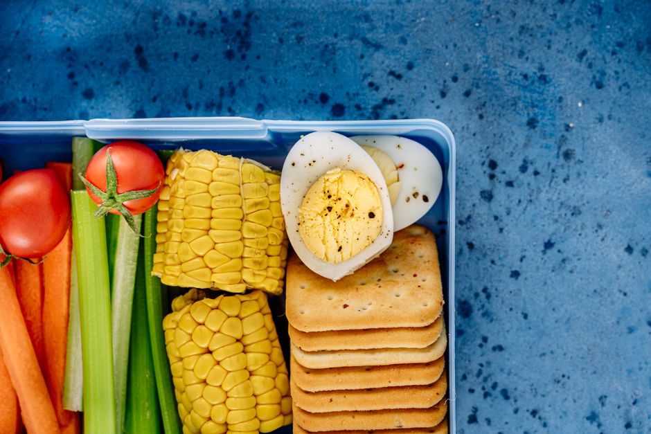 A backpack packed with healthy travel snacks: a reusable water bottle, a banana, a small bag of almonds, and a whole-grain energy bar.