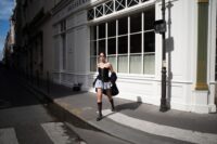 A stylish Parisian woman walking on a city street, wearing a beige trench coat, tailored trousers, and ballet flats, embodying Parisian minimalism.