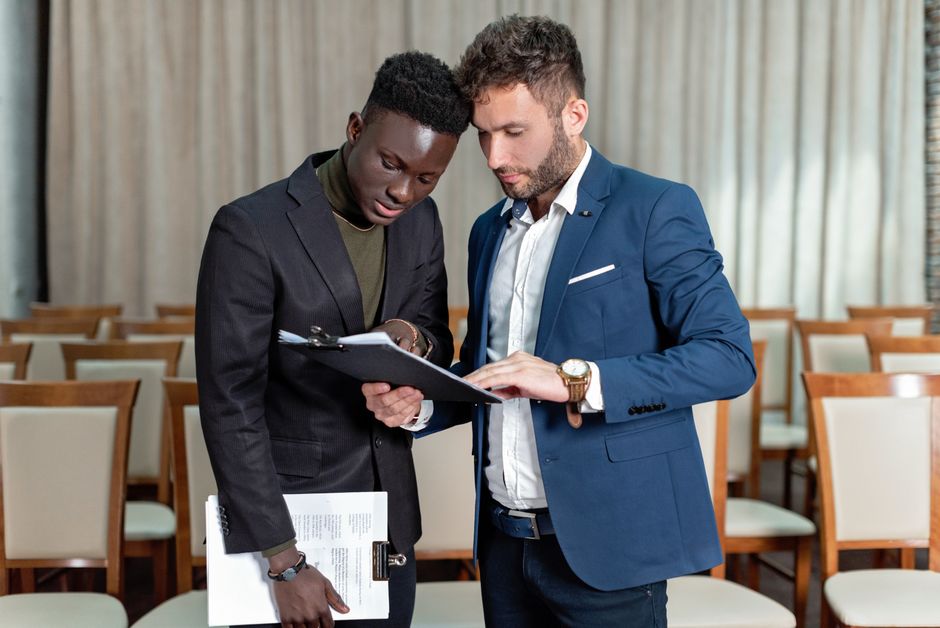 Two people, one pointing to a section of a detailed business contract, indicating careful review and discussion.