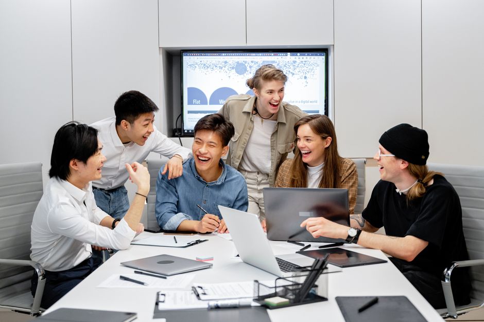 A group of diverse young people's hands holding various smartphones with different communication app icons visible.