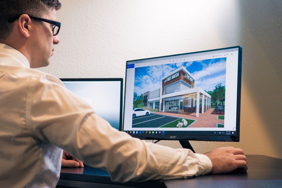 Overhead view of a person intently focused on a computer screen, designing a complex city layout in a simulation game.