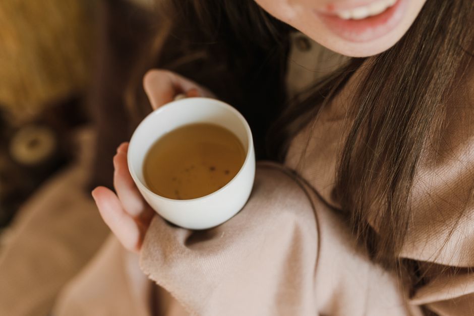 A person holding a warm mug of herbal tea, silhouetted against a dimly lit window in the evening, promoting relaxation for sleep.