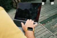 A remote worker staring at a laptop, surrounded by floating icons representing various software subscriptions and cloud services.