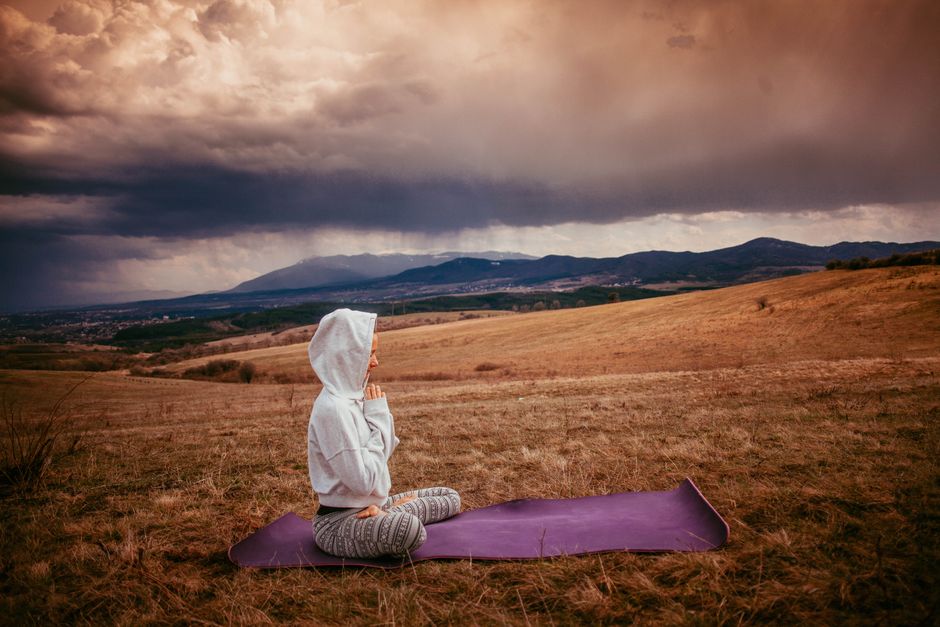 A person sitting cross-legged, eyes closed, in a sun-drenched, minimalist room, symbolizing a moment of quiet reflection and empty time.