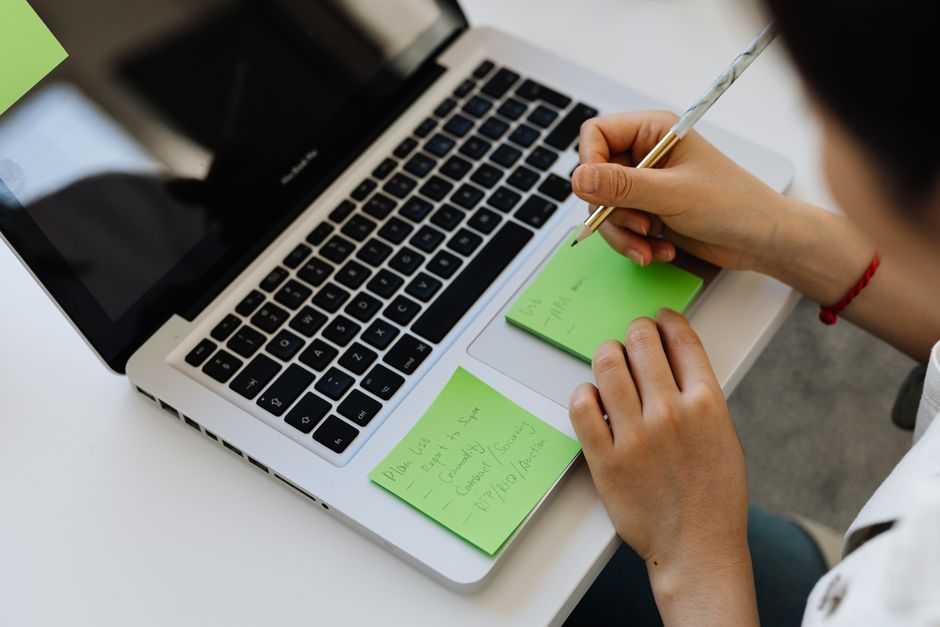 A person is intently looking at a laptop screen, which displays a note-taking application with various categorized notes, symbolizing the organization and searchability of a digital note hub.