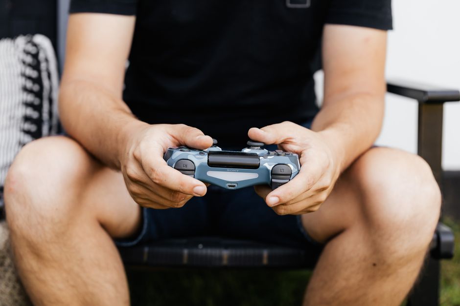 Someone holding a game controller, deeply absorbed in playing a narrative-driven video game on a screen, showing engaged gameplay.