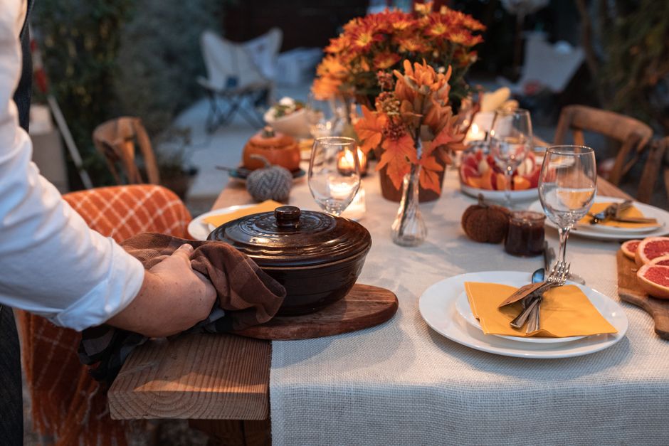 Hands carefully placing a cloth napkin and silverware on a dining table, suggesting intentional preparation for a meal.