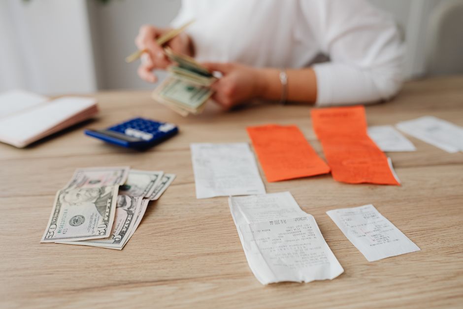 Hands sorting through a stack of envelopes and receipts on a tidy table, representing bill payment and organization.