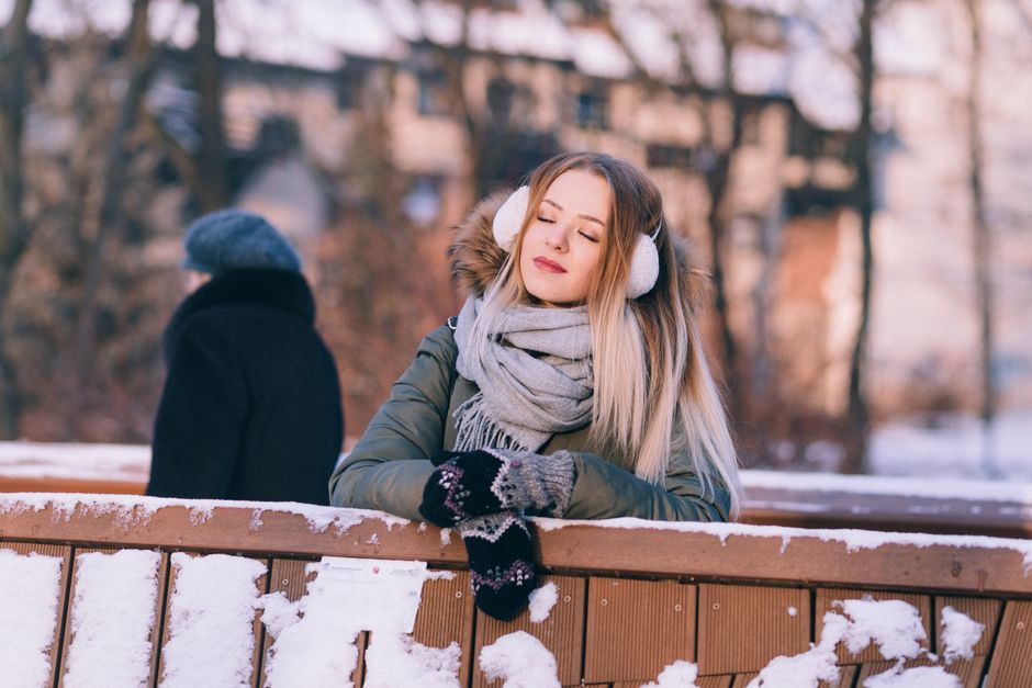 A person bundled in a chic, insulated parka, wool scarf, and warm hat navigates a snowy Montreal street, showcasing practical winter city commuter style.