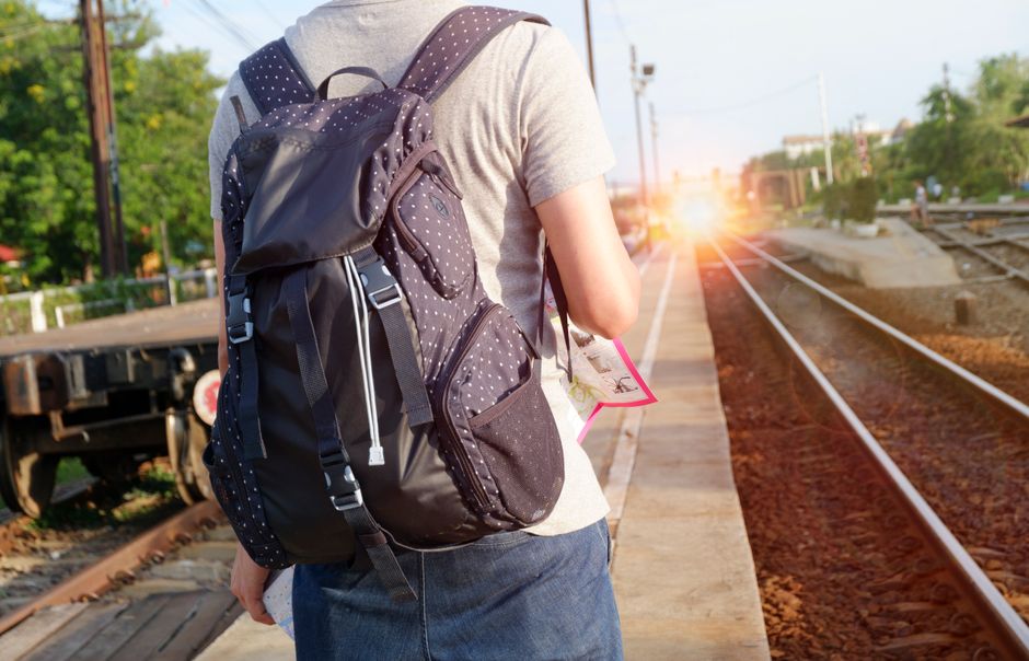 A solo traveler, wearing a backpack, consults a map in a scenic outdoor setting, embodying independent exploration.