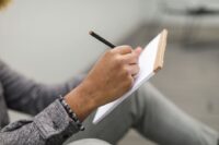 A person thoughtfully outlining a project brief on a tablet, surrounded by notes and a cup of coffee, symbolizing the detailed planning phase.