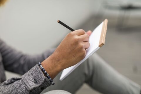 A person thoughtfully outlining a project brief on a tablet, surrounded by notes and a cup of coffee, symbolizing the detailed planning phase.