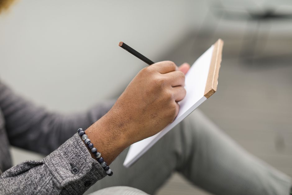 A person thoughtfully outlining a project brief on a tablet, surrounded by notes and a cup of coffee, symbolizing the detailed planning phase.
