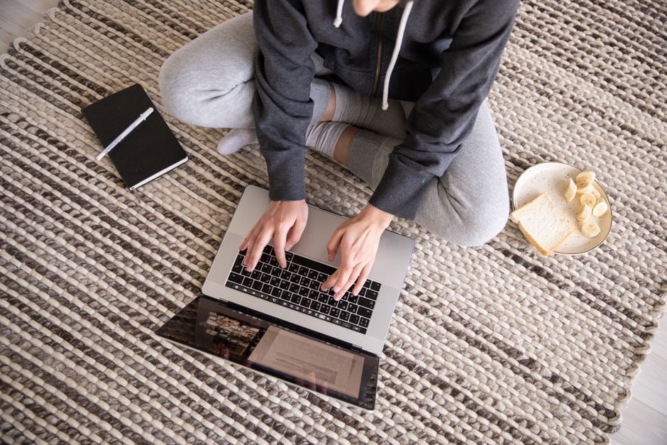 A person thoughtfully typing on a laptop, composing an email with a cup of coffee nearby, representing a personalized follow-up.