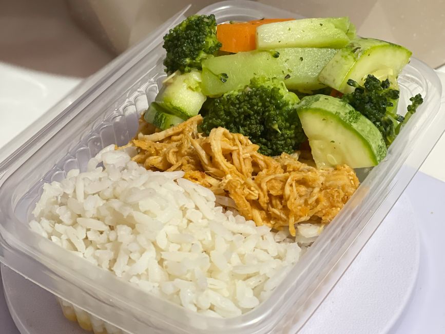 Several glass food storage containers filled with prepped ingredients: chopped vegetables, cooked chicken, and grains, ready for quick assembly.