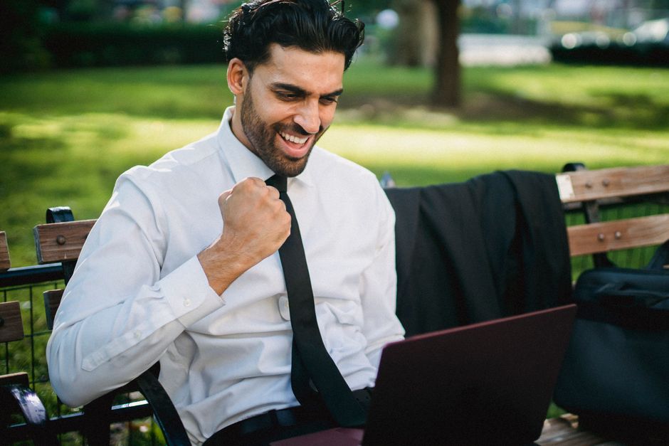 A remote worker with a laptop sitting on a bench in a beautiful park, taking a break from work to enjoy the scenery.