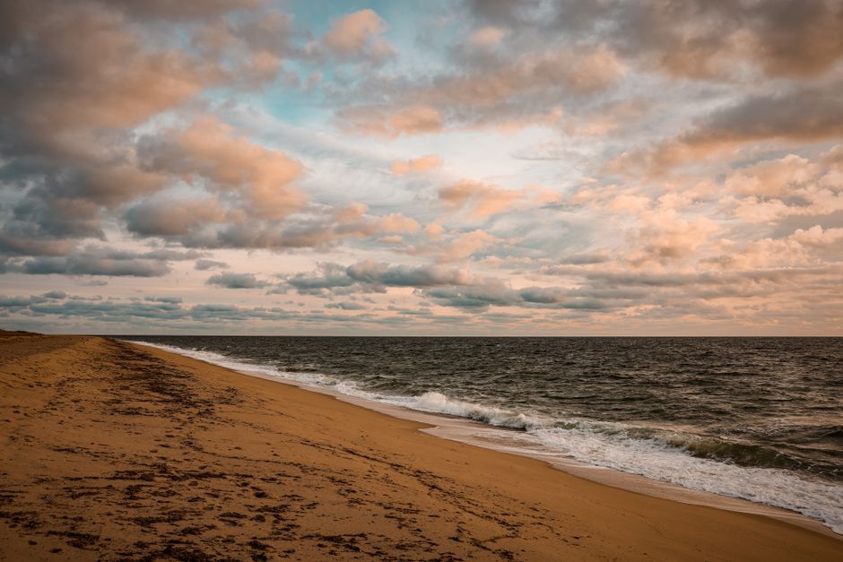 A stunning sunset over a secluded, empty beach with gentle waves lapping the shore, symbolizing peaceful coastal travel.