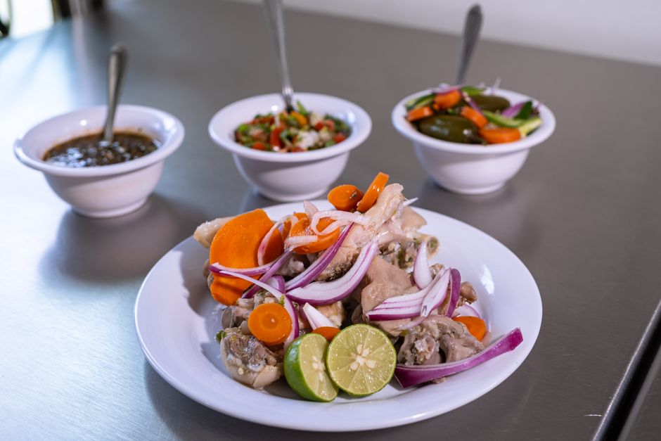 A bowl of shredded chicken surrounded by small bowls of different spices and herbs like cumin, chili powder, ginger, and lemon wedges, illustrating flavor transformation.