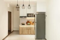 A very small, clean apartment kitchen with limited counter space and basic appliances, showing a single burner and a few neatly organized items.