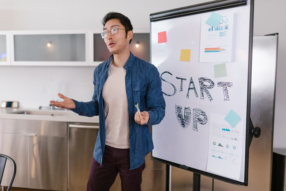 A small business owner pointing at a whiteboard with a clearly defined agenda, guiding a focused team meeting.