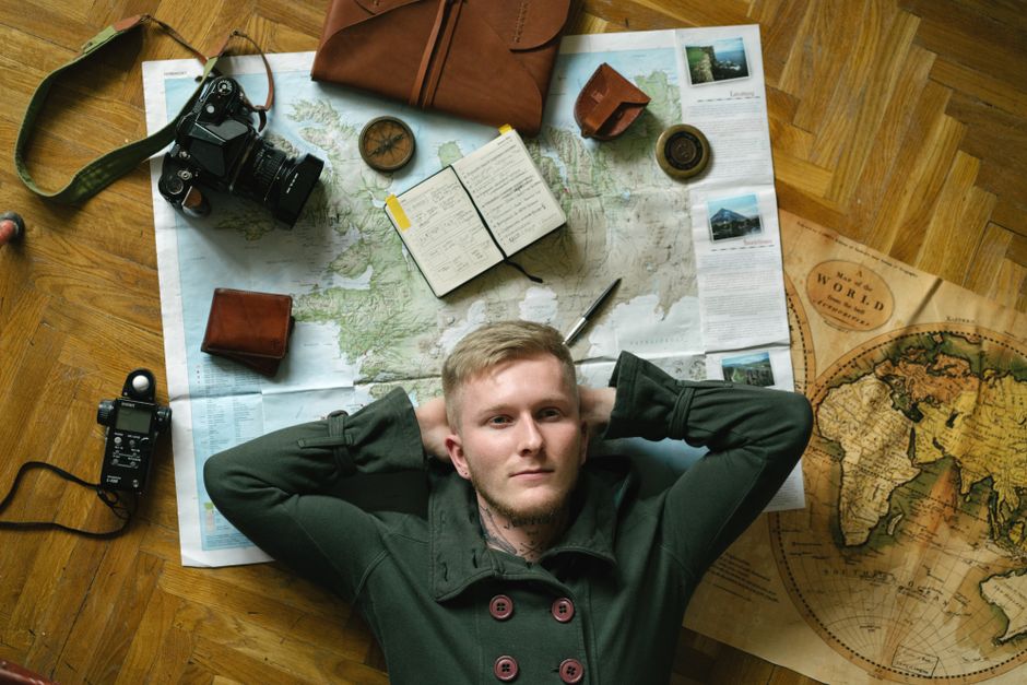 A small business owner sits at a desk, looking thoughtfully at a large world map tacked to the wall, with notes and markers indicating potential markets.