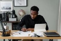 A small business owner reviewing a tablet displaying meeting notes and action items, looking focused.