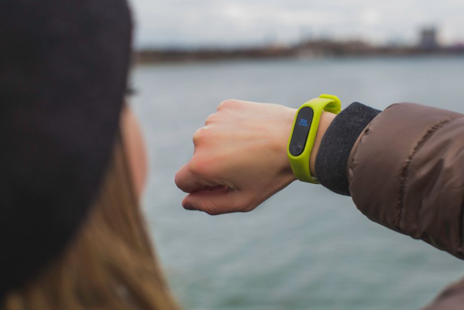 A smartwatch on a person's wrist, showing activity rings, with a blurred cityscape in the background, suggesting global connectivity.