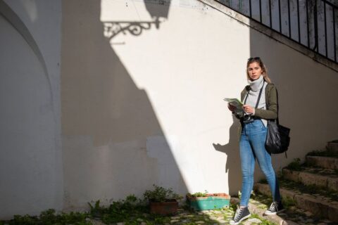 A solo female traveler admiring the intricate façade of an old building on a cobblestone street.
