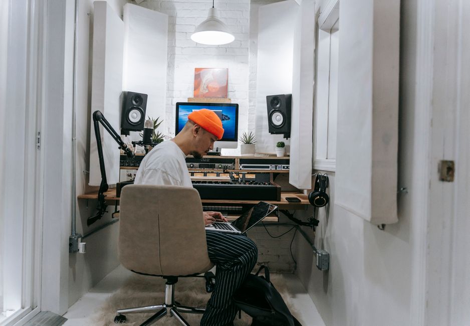A home office wall partially covered with subtle grey acoustic panels, a thick rug on the floor, and heavy drapes, showcasing effective sound dampening.