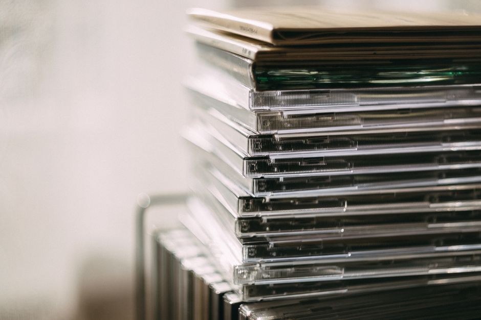 A dusty stack of physical video game cases on a shelf, symbolizing a neglected backlog of purchased but unplayed games.