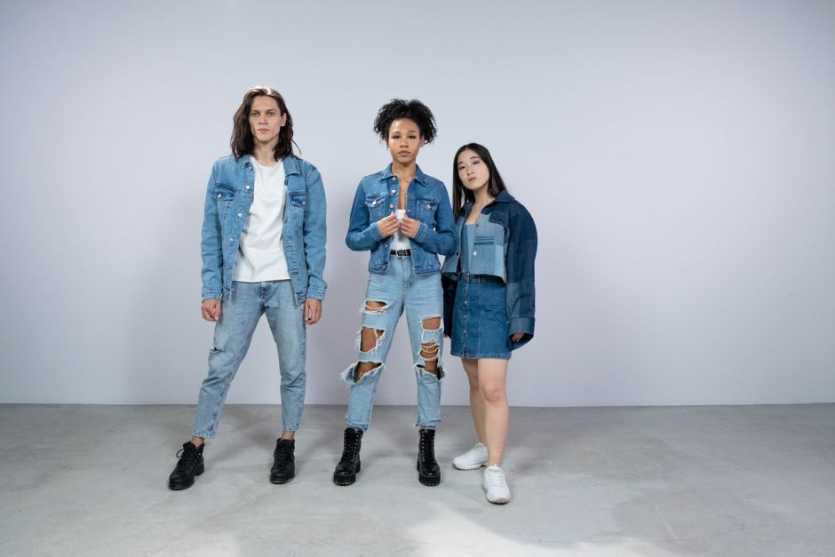 A flat lay showcasing a single statement jacket styled in five different outfit combinations, from formal trousers to casual jeans and a dress.