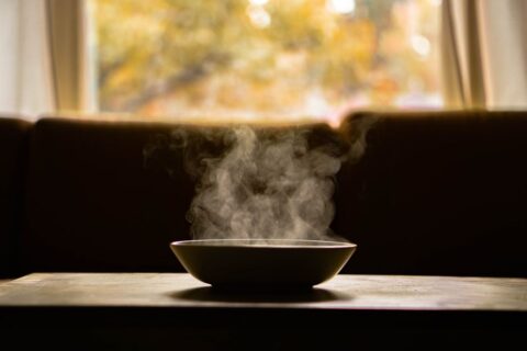 A steaming bowl of hearty lentil soup garnished with fresh parsley, sitting on a wooden table in a cozy, softly lit kitchen, perfect for a cold evening.