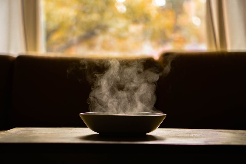 A steaming bowl of hearty lentil soup garnished with fresh parsley, sitting on a wooden table in a cozy, softly lit kitchen, perfect for a cold evening.