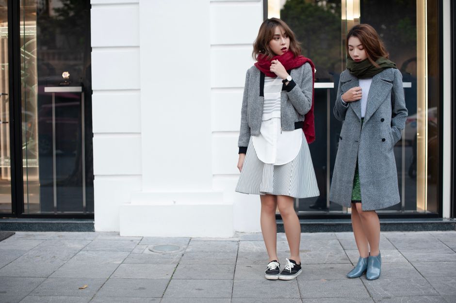 A stylish woman walking on a city street, showcasing a layered smart casual look with a trench coat, tailored pants, and comfortable flat shoes.
