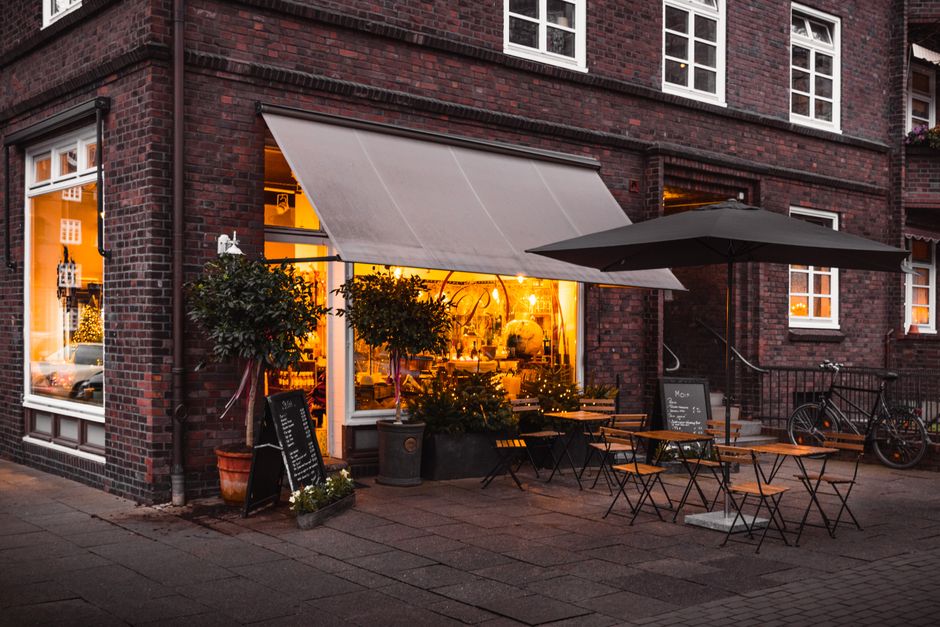 An inviting street-level view of a traditional European cafe, featuring outdoor tables and chairs, nestled within a historic city neighborhood.