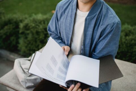 A student in a library setting, looking at various AI tool pricing plans on a laptop screen, with notes and pens nearby, illustrating the process of comparing subscriptions.