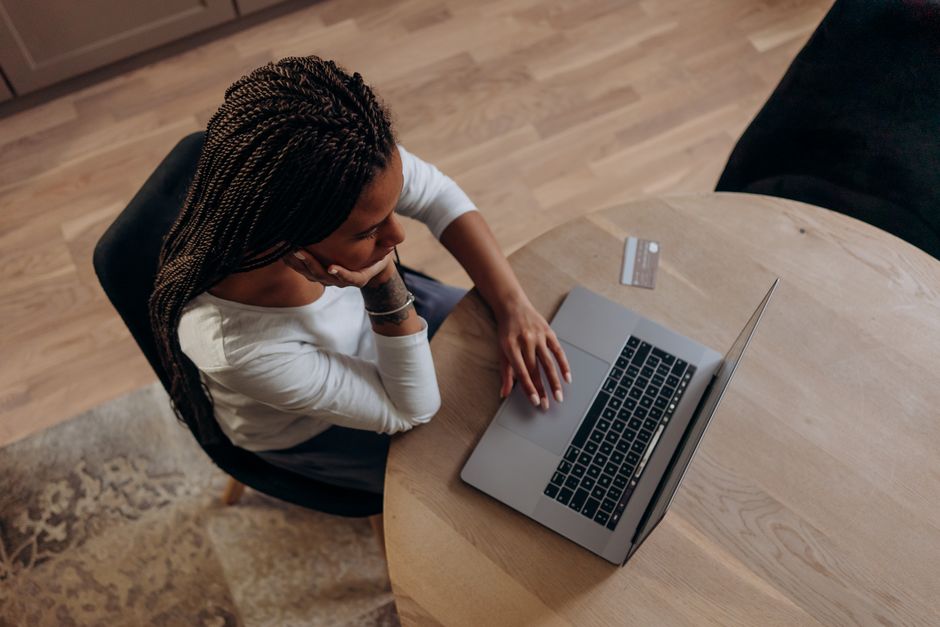A person with a calculator and a laptop, carefully reviewing subscription costs and benefits of different AI tools, emphasizing the financial decision-making process for students.