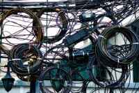 A drawer overflowing with a tangled mess of various charging cables and adapters, symbolizing cable clutter.