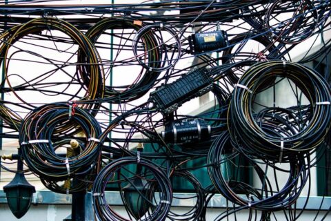 A drawer overflowing with a tangled mess of various charging cables and adapters, symbolizing cable clutter.