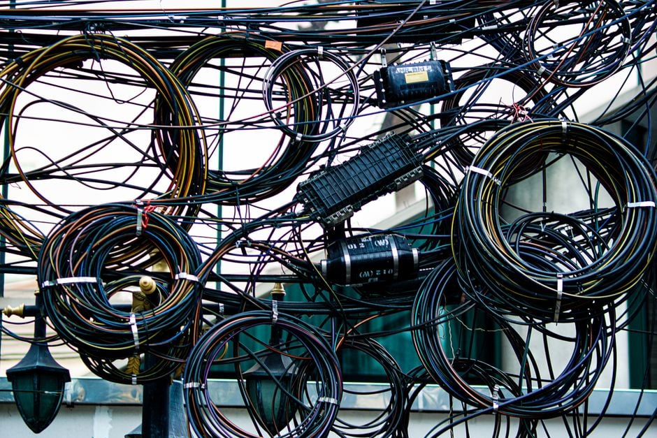A drawer overflowing with a tangled mess of various charging cables and adapters, symbolizing cable clutter.