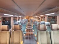Travelers relaxing in spacious seats inside a modern train car, enjoying the journey without airport stress.