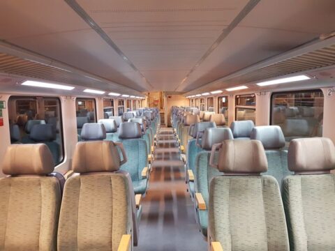 Travelers relaxing in spacious seats inside a modern train car, enjoying the journey without airport stress.