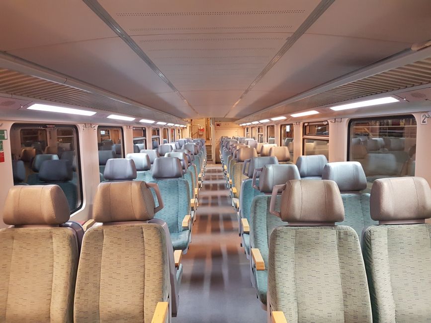 Travelers relaxing in spacious seats inside a modern train car, enjoying the journey without airport stress.