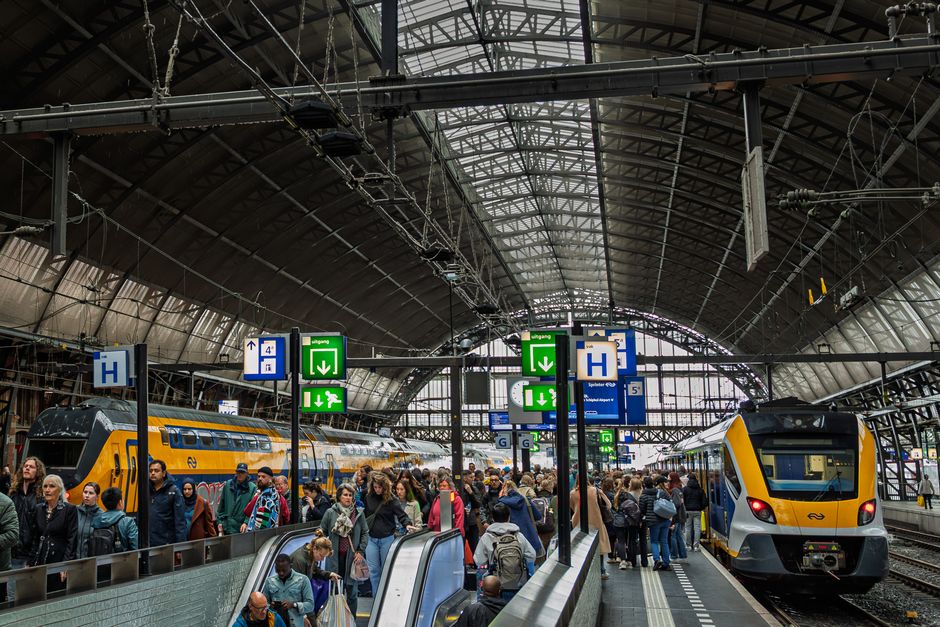 A busy train station concourse with people and trains, symbolizing travel connections for day trips.