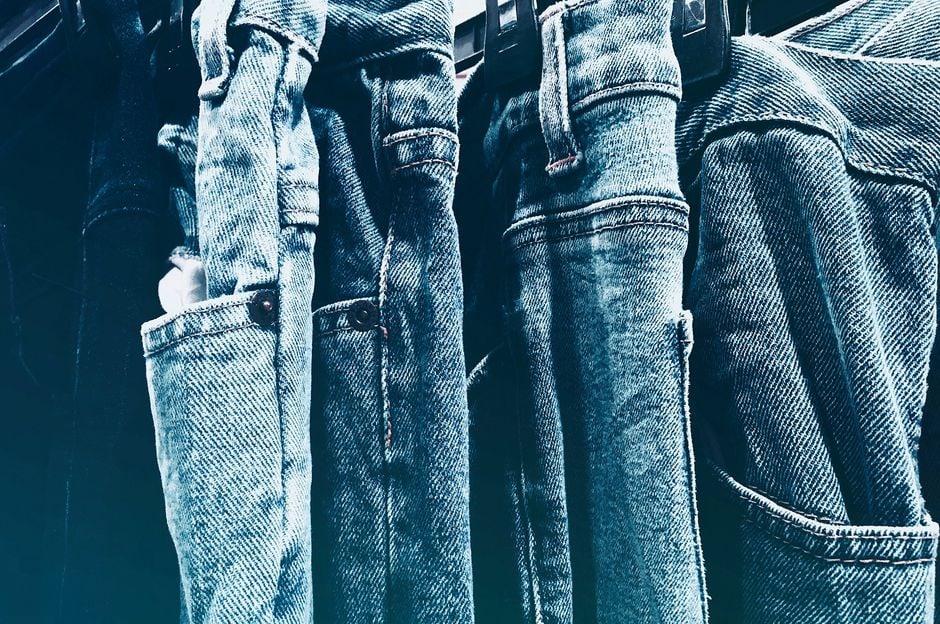 A close-up shot of different denim styles, showcasing the varied textures, washes, and fabric compositions of jeans ranging from dark indigo to light blue, emphasizing stretch and classic cuts.