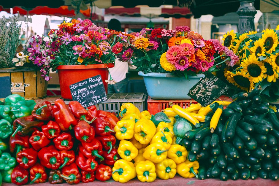 An overhead shot of a colorful farmers market stall overflowing with fresh, seasonal fruits and vegetables like leafy greens, berries, and root vegetables.
