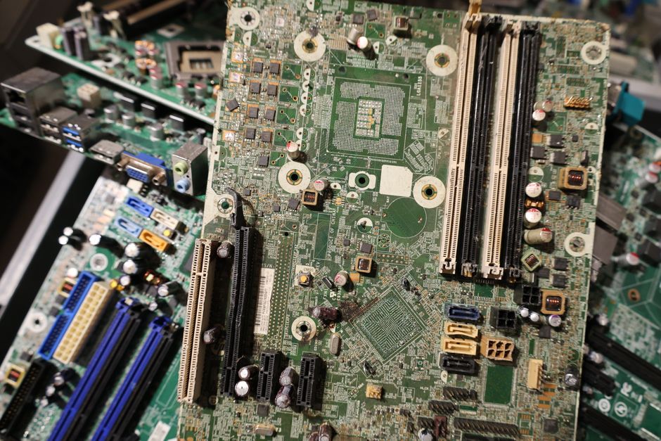 A busy, well-organized warehouse filled with shelves of various refurbished electronics, including smartphones and laptops, ready for inspection and packaging.