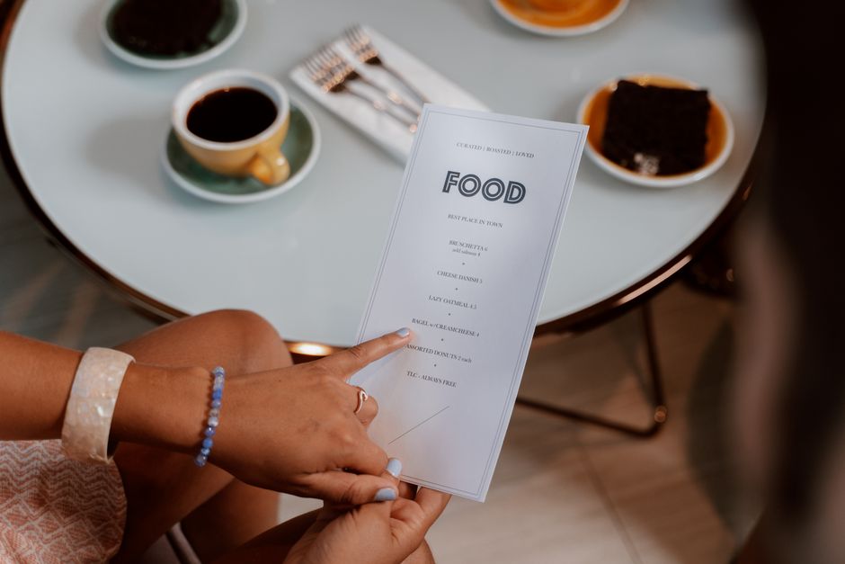 A person thoughtfully looking at a restaurant menu, pointing to a grilled fish option, demonstrating mindful selection for a balanced meal.